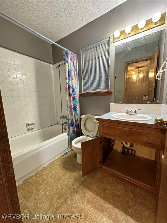 full bathroom featuring shower / tub combo with curtain, vanity, a textured ceiling, tile patterned floors, and toilet