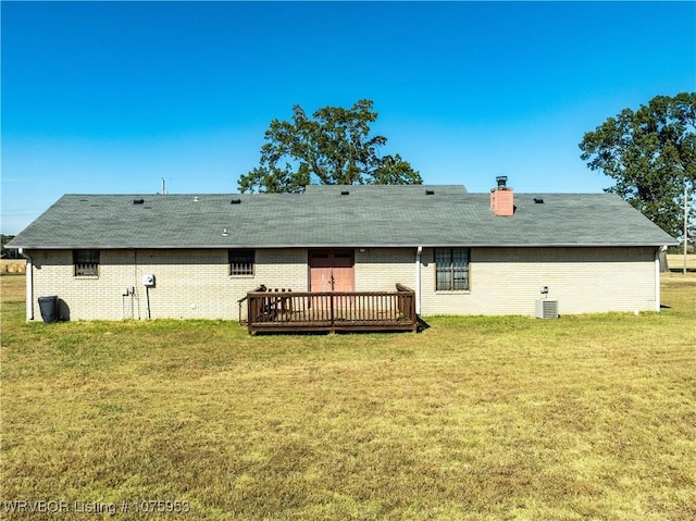 rear view of property featuring cooling unit, a deck, and a lawn