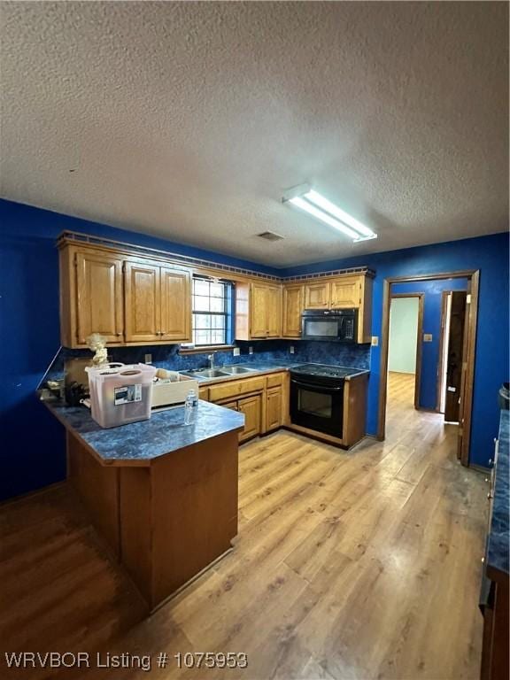 kitchen with sink, light hardwood / wood-style flooring, black appliances, a textured ceiling, and kitchen peninsula