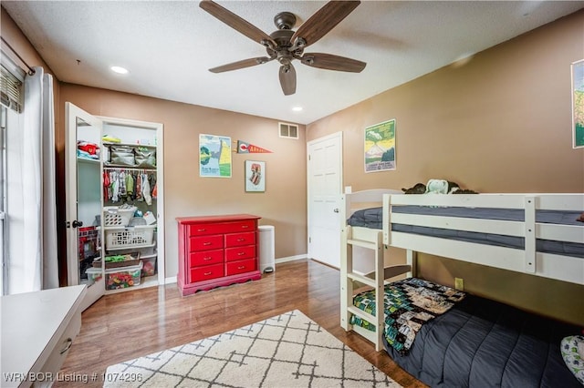 bedroom with ceiling fan, wood-type flooring, a textured ceiling, and a closet