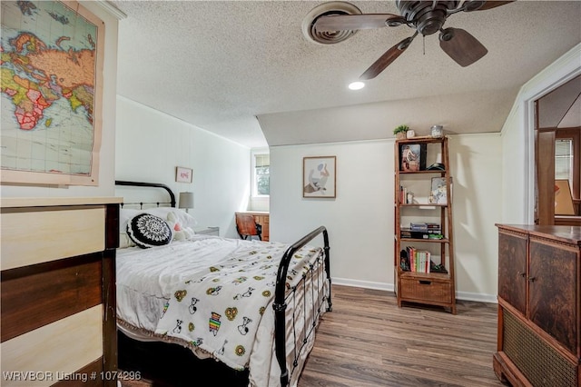 bedroom with ceiling fan, wood-type flooring, and a textured ceiling