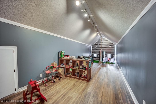 rec room featuring rail lighting, ornamental molding, a textured ceiling, vaulted ceiling, and hardwood / wood-style floors