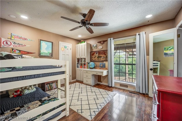 bedroom with ceiling fan, dark wood-type flooring, and a textured ceiling