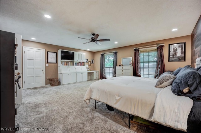 bedroom with a textured ceiling, light colored carpet, and ceiling fan