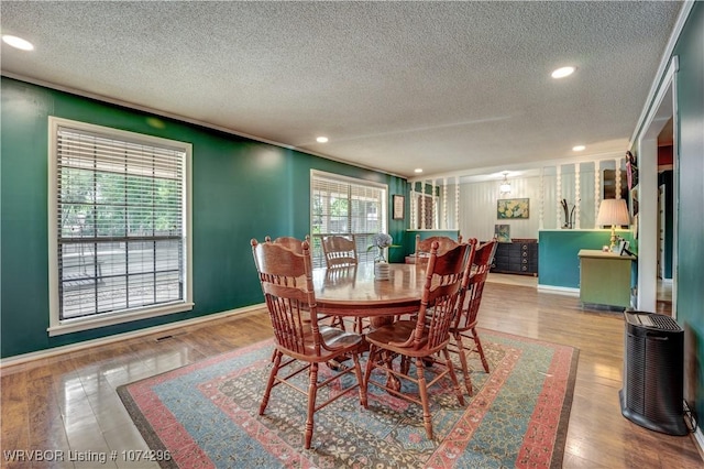 dining room with wood-type flooring and a textured ceiling