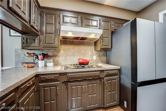 kitchen featuring backsplash, dark brown cabinetry, and appliances with stainless steel finishes