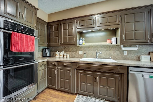 kitchen featuring decorative backsplash, light wood-type flooring, sink, and appliances with stainless steel finishes