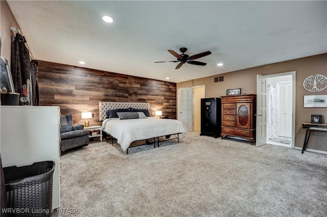 carpeted bedroom featuring ceiling fan and wood walls