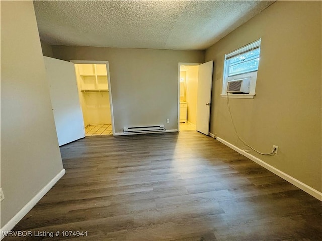 unfurnished bedroom with baseboard heating, cooling unit, wood-type flooring, a textured ceiling, and a closet