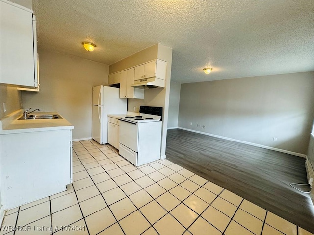 kitchen featuring a textured ceiling, white appliances, sink, light tile patterned floors, and white cabinetry