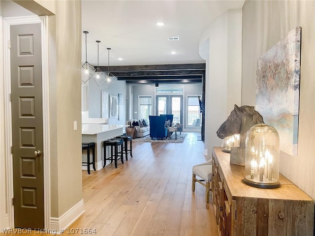 corridor featuring french doors, light hardwood / wood-style floors, and beam ceiling