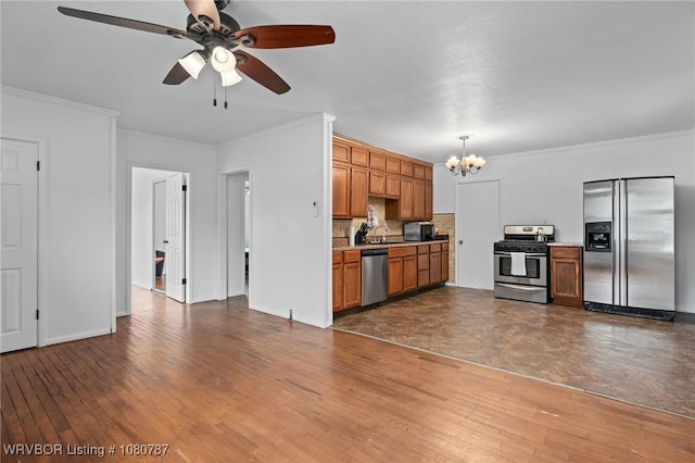 kitchen with stainless steel appliances, ceiling fan with notable chandelier, crown molding, light countertops, and dark wood-style floors