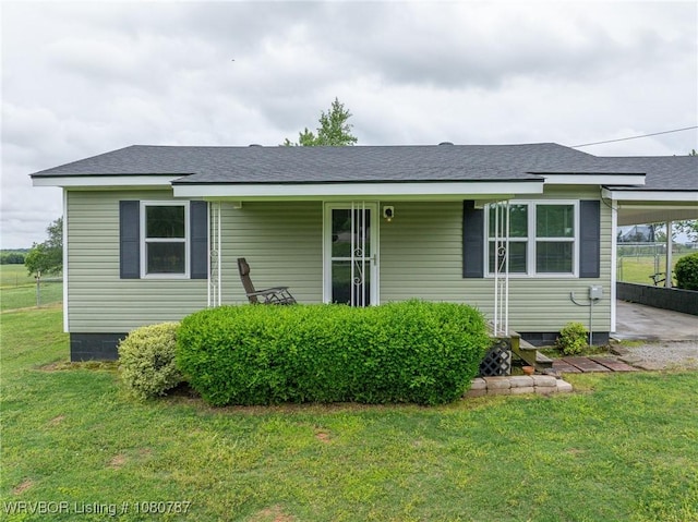 view of front of property featuring a front yard, an attached carport, and a shingled roof