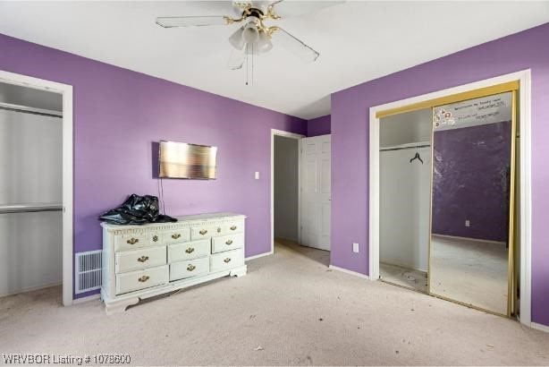 unfurnished bedroom featuring light carpet, two closets, and ceiling fan