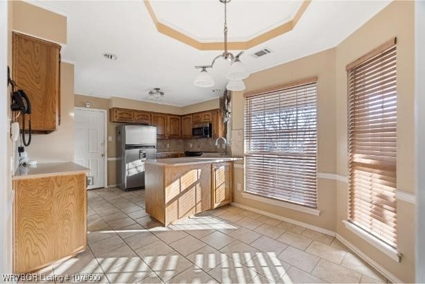 kitchen with light tile patterned flooring, appliances with stainless steel finishes, sink, hanging light fixtures, and a raised ceiling