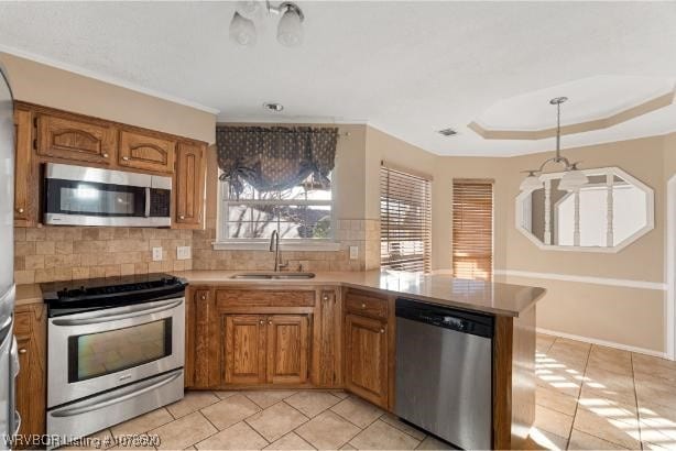 kitchen with sink, tasteful backsplash, appliances with stainless steel finishes, kitchen peninsula, and a raised ceiling