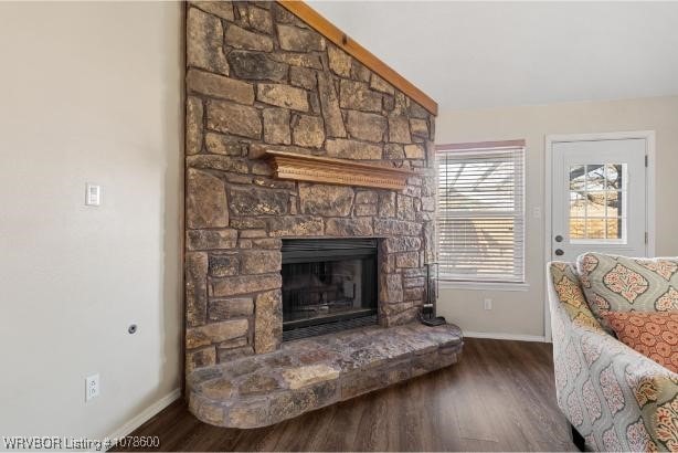 sitting room with dark hardwood / wood-style flooring, a stone fireplace, and lofted ceiling