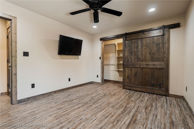 interior space with recessed lighting, a barn door, baseboards, and wood finished floors