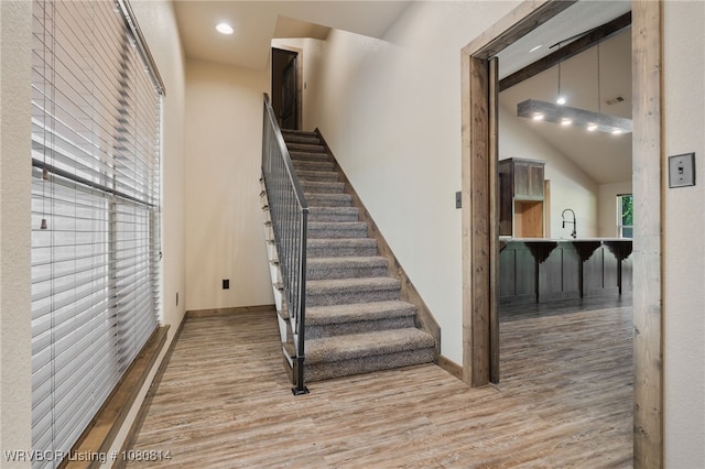 stairway with a towering ceiling, wood finished floors, baseboards, and recessed lighting