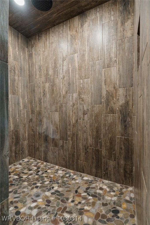 full bathroom featuring tiled shower and stone flooring