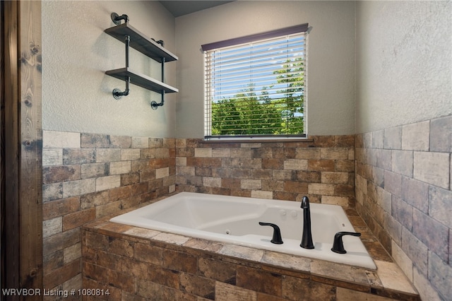full bath featuring a tub with jets and a textured wall