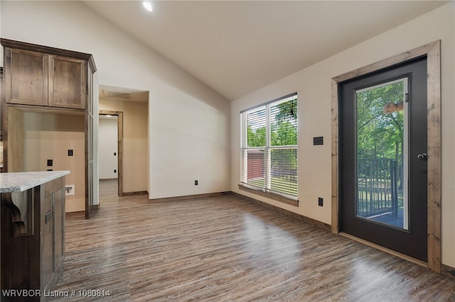 unfurnished living room featuring vaulted ceiling, baseboards, and wood finished floors
