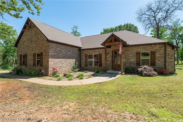 view of front of property with a shingled roof, a front lawn, and brick siding