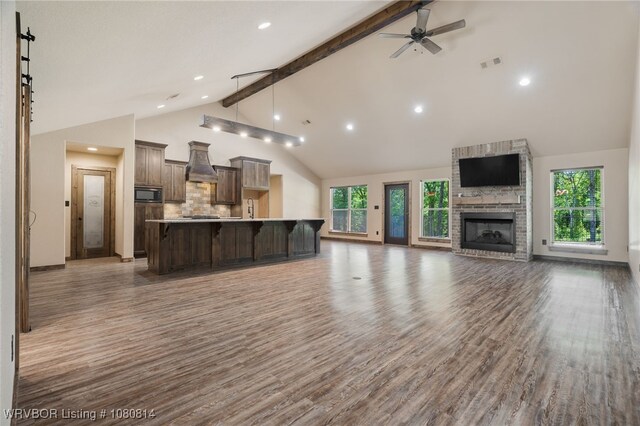 unfurnished living room with ceiling fan, visible vents, high vaulted ceiling, wood finished floors, and beam ceiling