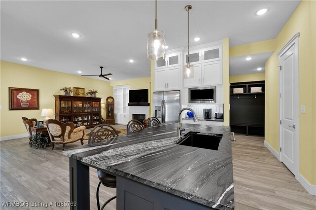9100 Kirkwood Rd, Fort Smith, AR 72916 - kitchen featuring stainless steel fridge with ice dispenser, a ceiling fan, a center island with sink, white cabinetry, and light wood-style flooring