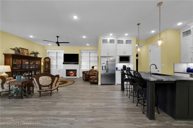 9100 Kirkwood Rd, Fort Smith, AR 72916 - living room with ceiling fan, wood finished floors, a warm lit fireplace, and recessed lighting