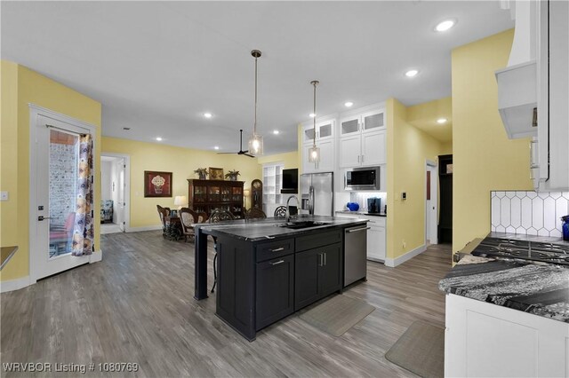 9100 Kirkwood Rd, Fort Smith, AR 72916 - kitchen with stainless steel appliances, white cabinets, light wood-style flooring, dark countertops, and decorative backsplash