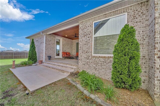 9100 Kirkwood Rd, Fort Smith, AR 72916 - view of exterior entry featuring a ceiling fan, brick siding, a patio, and a lawn