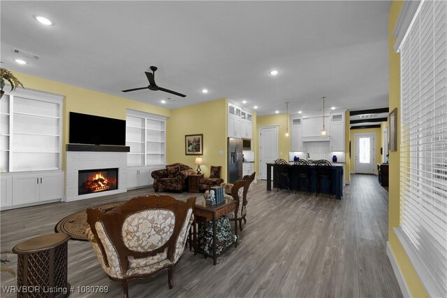 9100 Kirkwood Rd, Fort Smith, AR 72916 - living area featuring a ceiling fan, wood finished floors, a glass covered fireplace, recessed lighting, and built in shelves