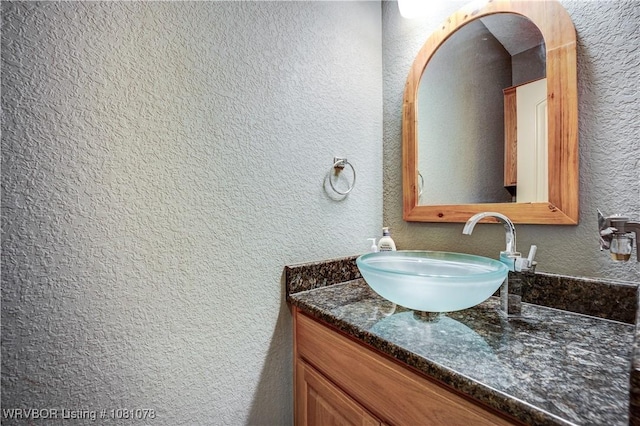 bathroom with a textured wall and vanity