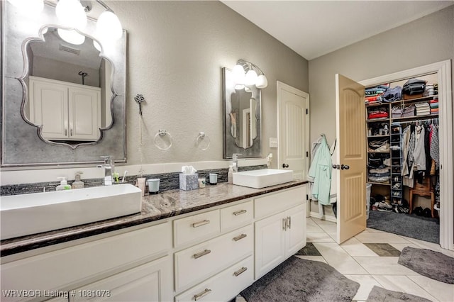 full bath with tile patterned flooring, double vanity, and a spacious closet