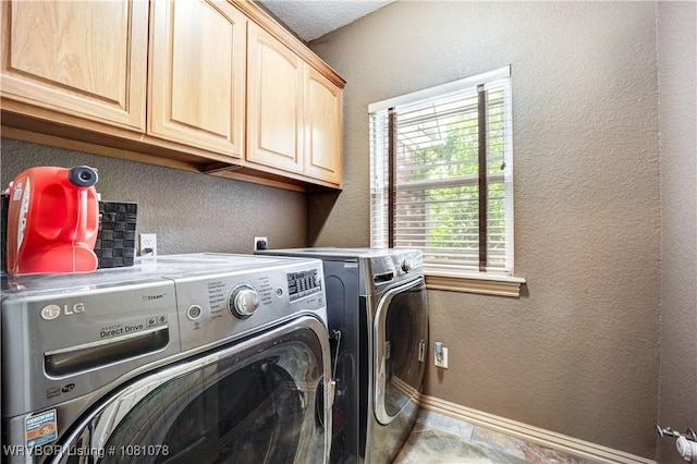 laundry room with washing machine and clothes dryer, a textured wall, cabinet space, and baseboards