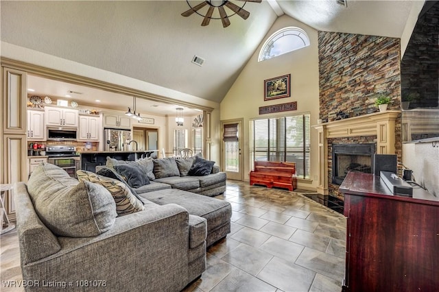 living area with high vaulted ceiling, a ceiling fan, and a fireplace