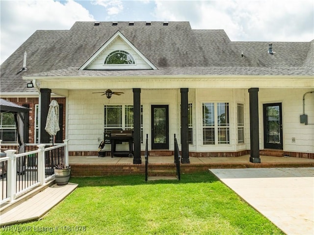 view of front of home featuring ceiling fan, a shingled roof, a front lawn, and covered porch