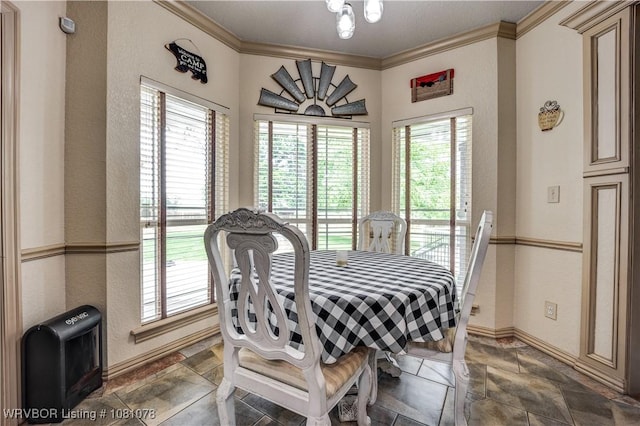 dining space featuring stone tile floors, healthy amount of natural light, crown molding, and baseboards