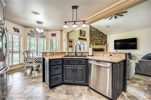 kitchen with appliances with stainless steel finishes, a sink, open floor plan, pendant lighting, and light stone counters