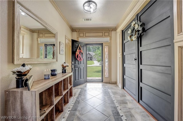 foyer entrance featuring inlaid floor details, ornamental molding, baseboards, a textured ceiling, and light tile patterned floors