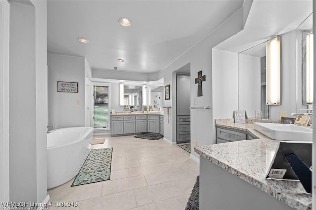 10301 Stoneleige St, Fort Smith, AR 72908 - bathroom featuring a freestanding bath, two vanities, tile patterned flooring, recessed lighting, and baseboards