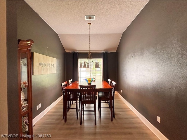 2420 Keystone Cir, Mulberry, AR 73947 - dining area featuring lofted ceiling, wood finished floors, and a textured ceiling