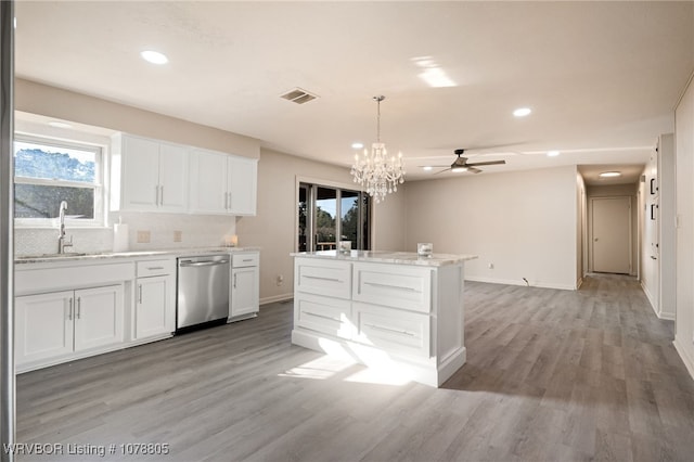 kitchen featuring pendant lighting, sink, dishwasher, white cabinetry, and light hardwood / wood-style floors