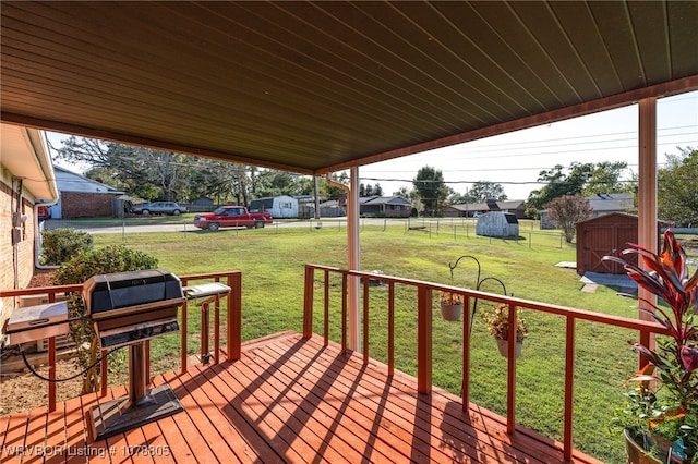 wooden deck featuring a shed, a lawn, and area for grilling