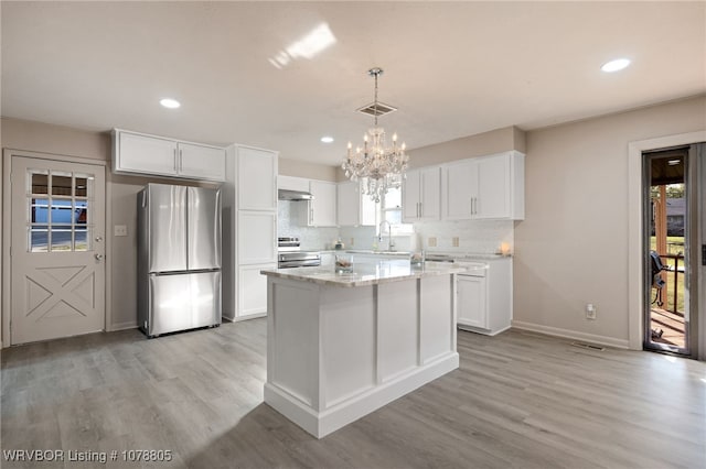 kitchen featuring decorative light fixtures, stainless steel appliances, white cabinets, and a kitchen island