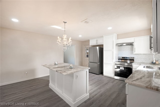 kitchen with stainless steel appliances, a center island, light stone countertops, white cabinets, and decorative light fixtures