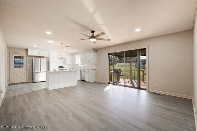 unfurnished living room featuring ceiling fan with notable chandelier and light wood-type flooring