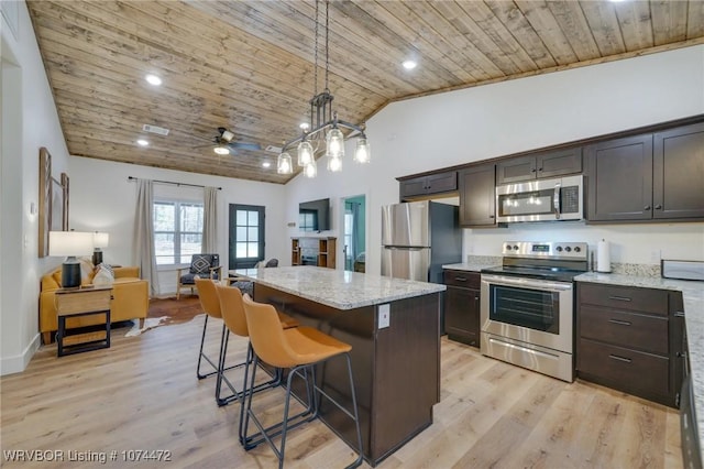 kitchen featuring stainless steel appliances, light stone counters, pendant lighting, a kitchen island, and wood ceiling