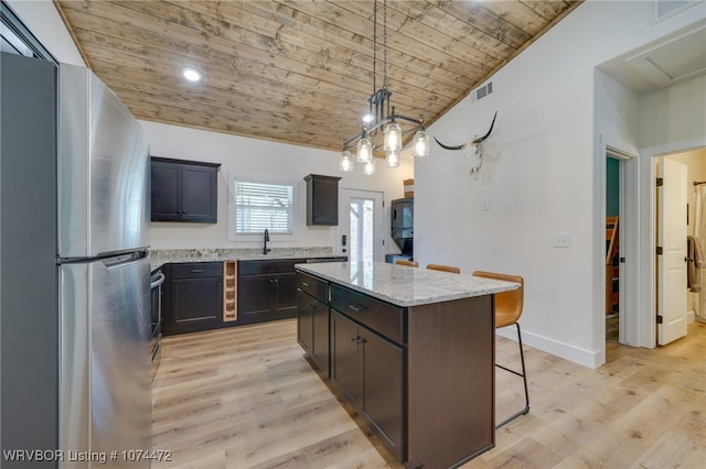 kitchen with pendant lighting, stainless steel fridge, a kitchen island, and wood ceiling